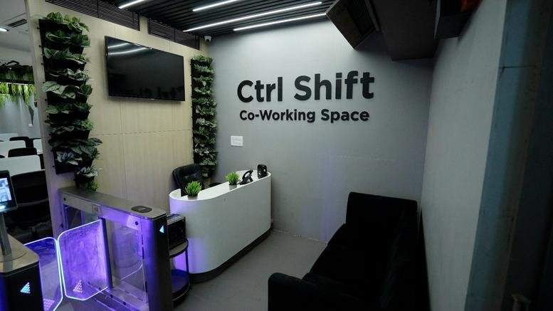 Modern reception area at Kohinoor Commercial Premises with branded wall and green plant accents.