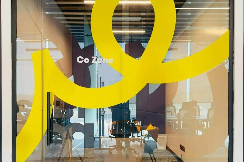 Entrance to the Co Zone at 2661, الامير سلطان showing glass walls with yellow graphics.