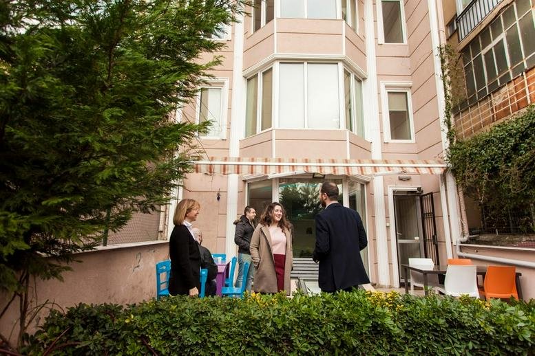 People chatting in the front courtyard of the peach-toned building at 3 / 1, İstasyon Yolu Sokağı.