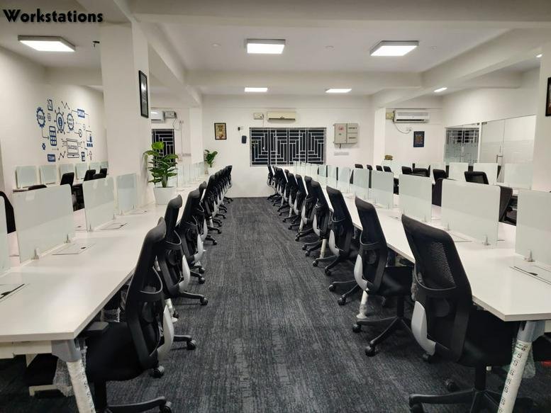 Spacious open-plan workstations at 320, Service Road featuring long white desks and black ergonomic chairs.