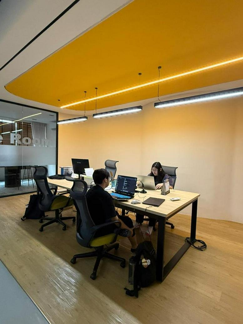 Interior view of a modern workspace with collaborative desks and yellow accents.