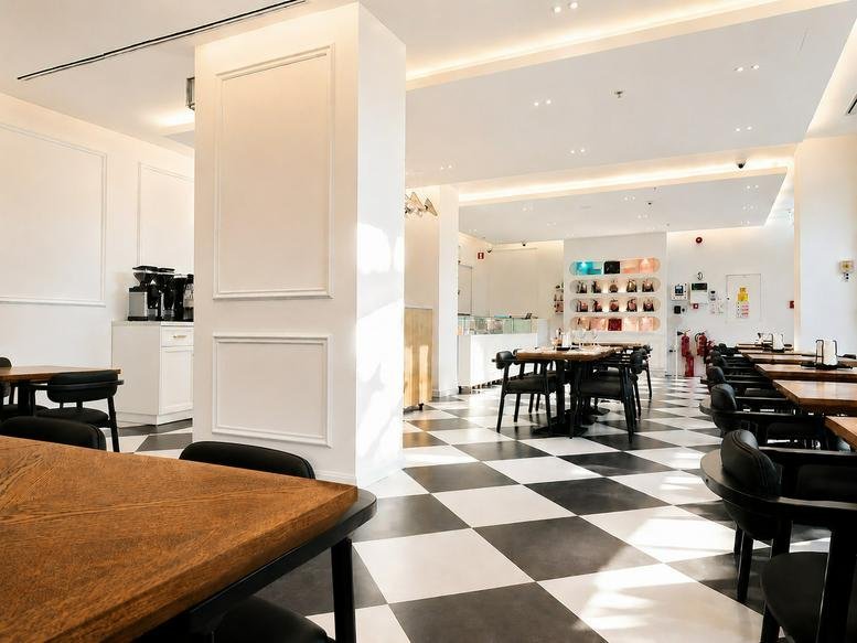 Spacious cafe and lounge area at 3C, Expo Village Boulevard, Building 3D with checkered floors and wooden tables.