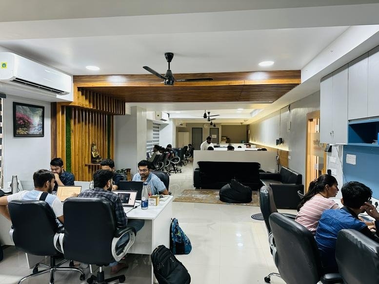 Collaborative office environment featuring wooden ceiling accents and black ergonomic chairs.