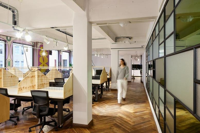 Open-plan workspace with timber-partitioned desks and parquet flooring.