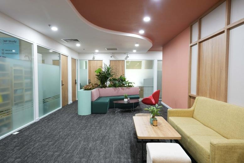Spacious common area with curved ceilings, colorful seating, and lush indoor plants at 60, Nguyễn Đình Chiểu.