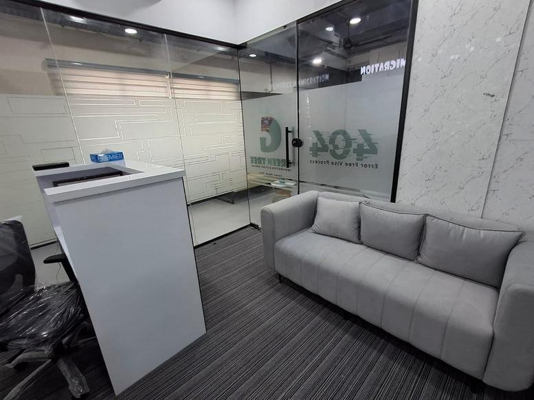 Modern reception area at 74A, Salai Rd featuring a grey sofa and a sleek white desk.