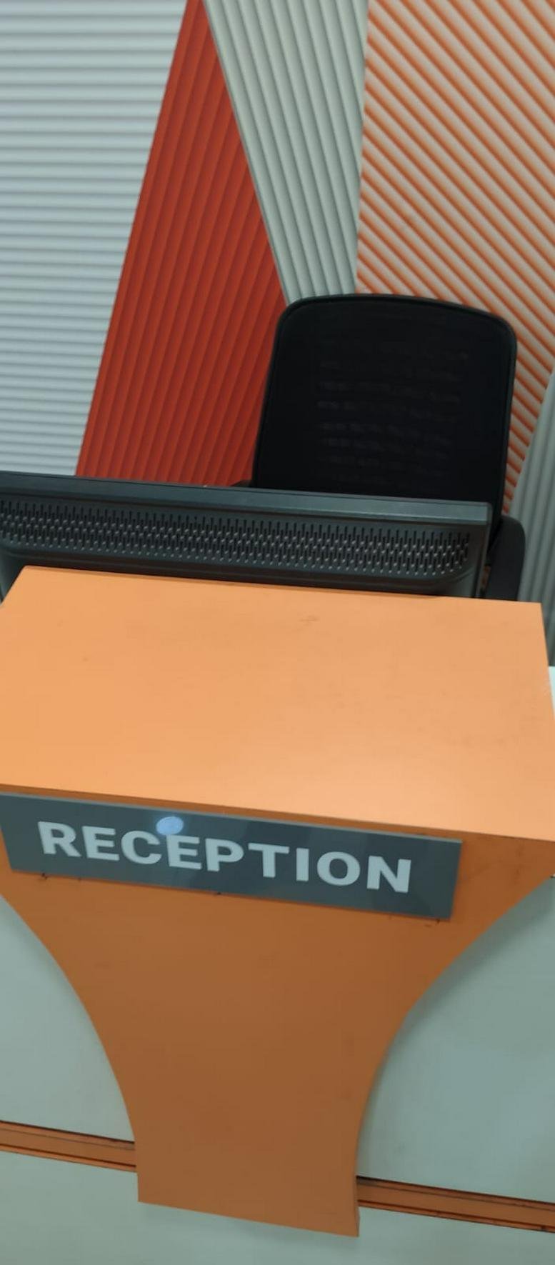 Reception desk at 813, Manjeera Majestic Commercial with a bright orange facade and modern signage.