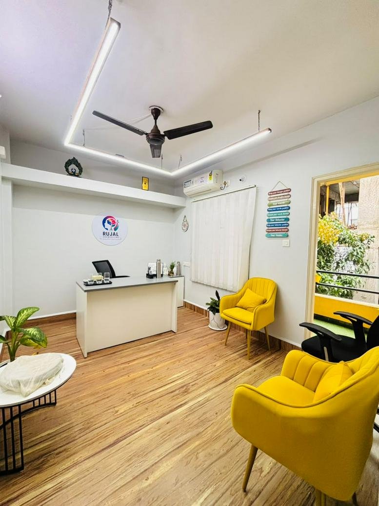 Reception area at 82/42 with a white desk, bright yellow armchairs, and warm wood-style flooring.