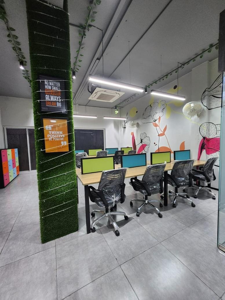 Open-plan coworking area at A-19A, Mayapuri Industrial Area with modern desks and vibrant wall art.