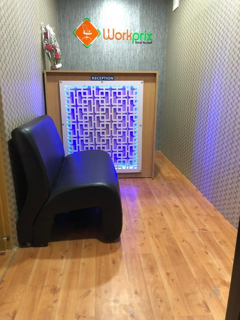 Reception area at The Bloom Co-Work with a glowing geometric desk and comfortable black seating.