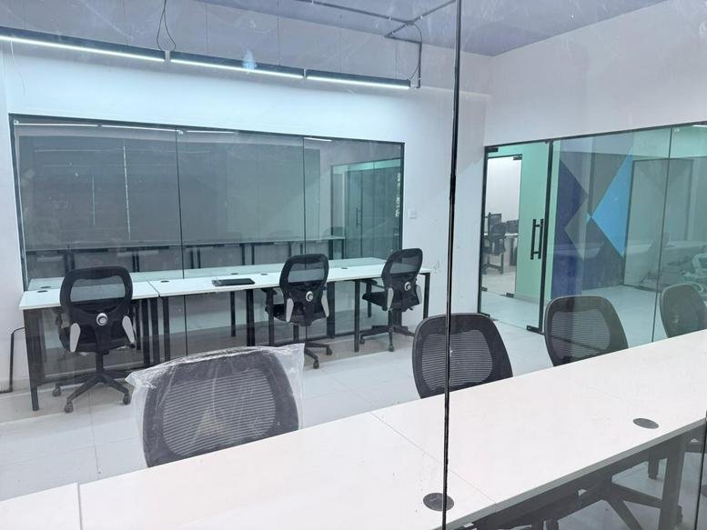 Spacious open-plan office space at Ajmera Nucleus with glass-walled suites and several workstations.