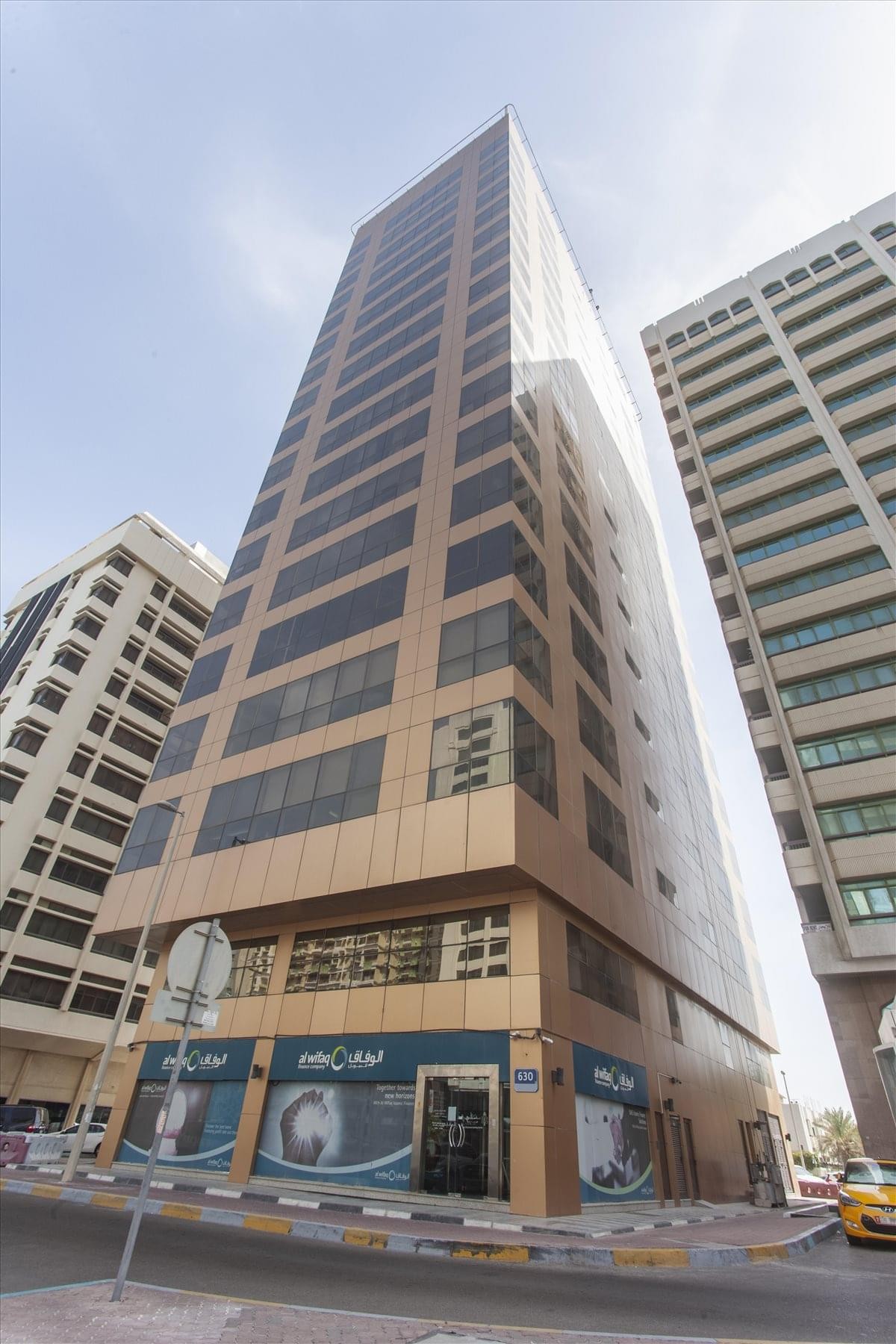 Exterior view of the Al Ghaith Holding Tower, a modern high-rise office building with a golden-brown facade.