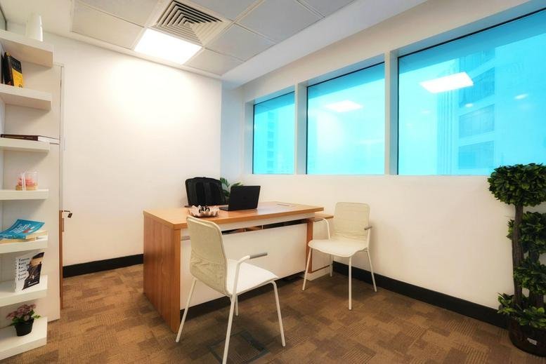 Bright private office at Al Jazzera with wooden desk, white chairs, and large windows.