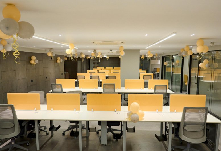 Spacious open-plan office at Anam 2 with yellow partitions and festive balloon decorations.