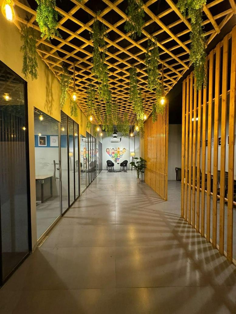 Bright hallway at AR Plaza with a wooden lattice ceiling, hanging greenery, and glass-walled offices.