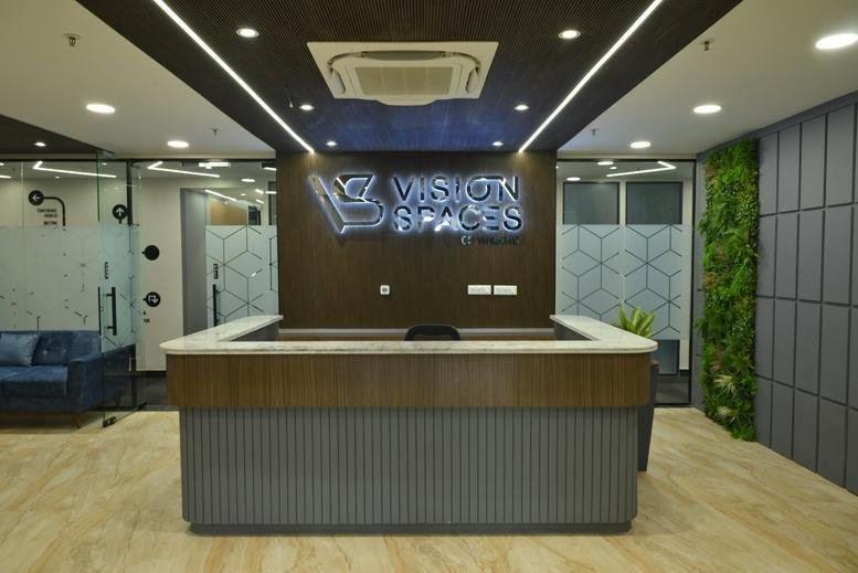 Reception area at BBD Viraj Tower, 4th Floor with wood accents and a green feature wall.