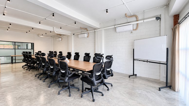 Wide view of a large meeting room featuring a whiteboard and track lighting.