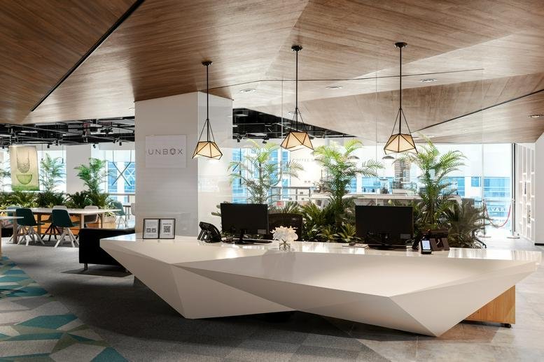 Bright reception area of Building 4, 2nd Floor featuring a geometric white desk and warm wood ceilings.
