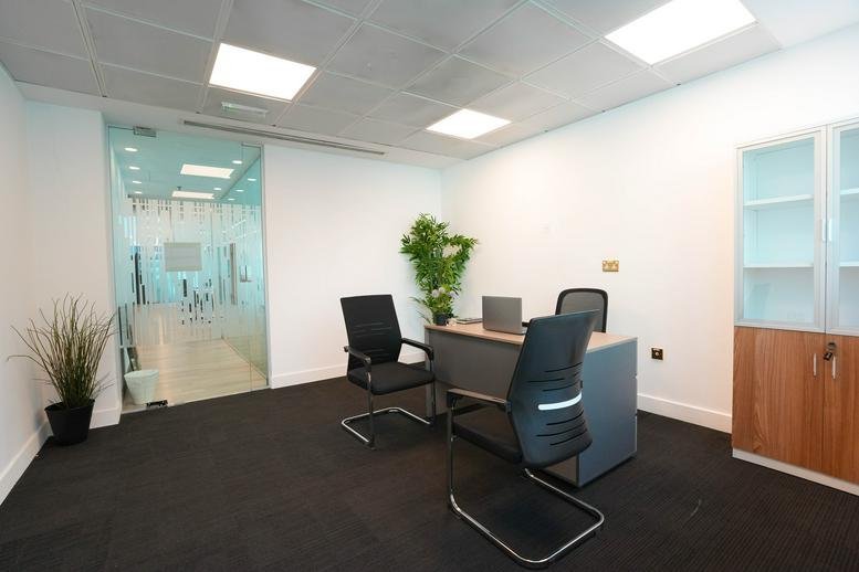 Two-person office with black chairs and greenery.