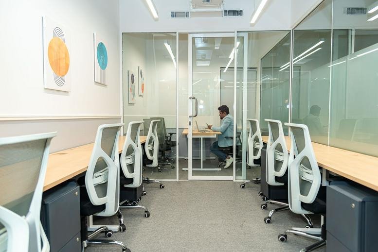 Shared office space with white ergonomic chairs and glass partitions at 101, Mathura Road, NH-19.