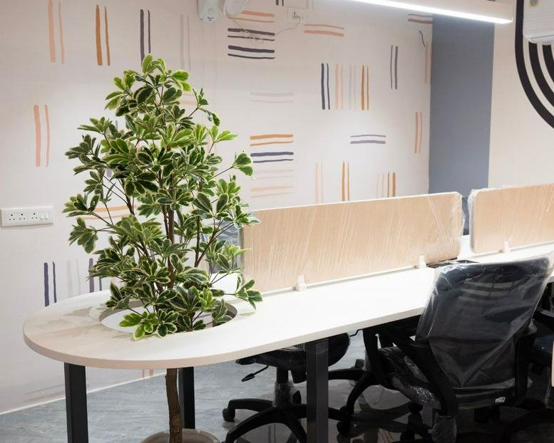 Bright coworking area at 11, Manewada Road, Nagpur featuring a curved desk with an integrated leafy plant.