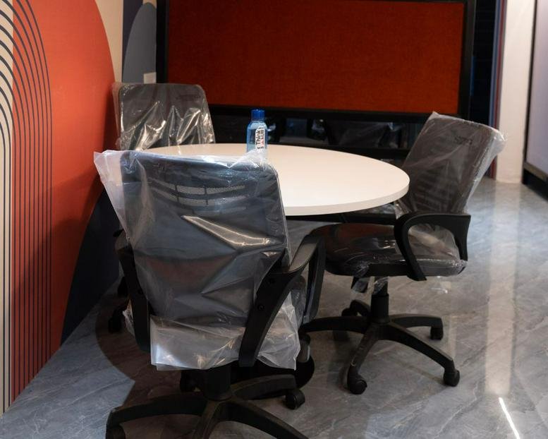 Small meeting area at 11, Manewada Road, Nagpur featuring a round white table and chairs with protective covers.