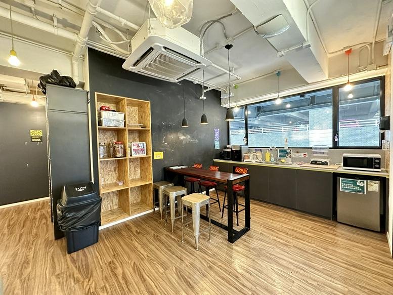 Communal kitchen area at 118 Wai Yip Street with high table and wooden shelving.