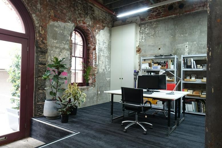 Workspace at 166, Albert Street, East Melbourne with exposed brick walls, arched windows, and indoor plants.