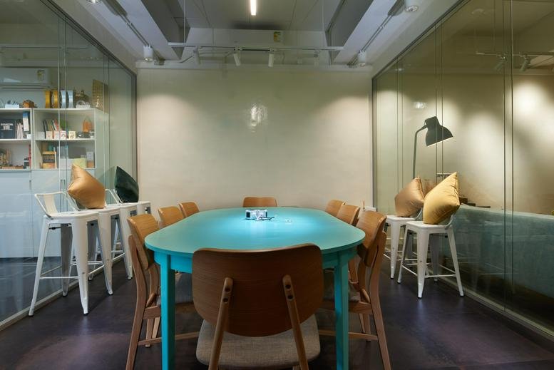 Meeting room at BUPA Centre with a vibrant turquoise table and modern wooden chairs.
