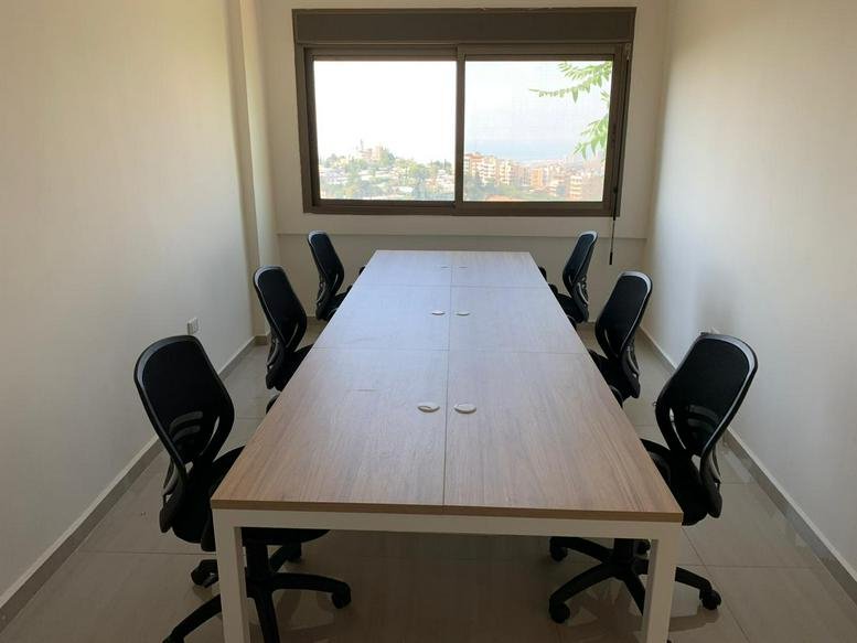 Meeting room at 20 Street 17 with a light wood table, black mesh chairs, and a window view.