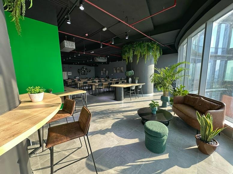 Modern coworking space at 2712 Addax Tower, Reem Island, featuring a lounge, green accent wall, and city views.