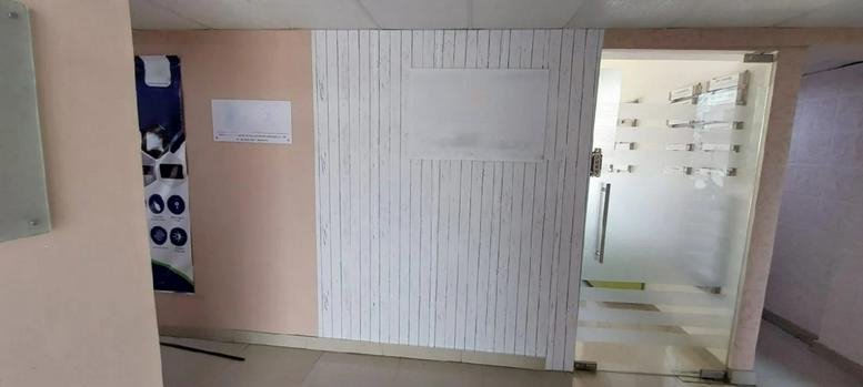 Bright reception area with white wood-paneled feature wall and glass door entrance at 28/A, 80 Feet Road, Bangalore.