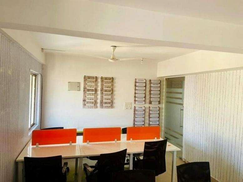 Open-plan workspace at 28/A, 80 Feet Road, Bangalore featuring desks with orange privacy screens and black chairs.
