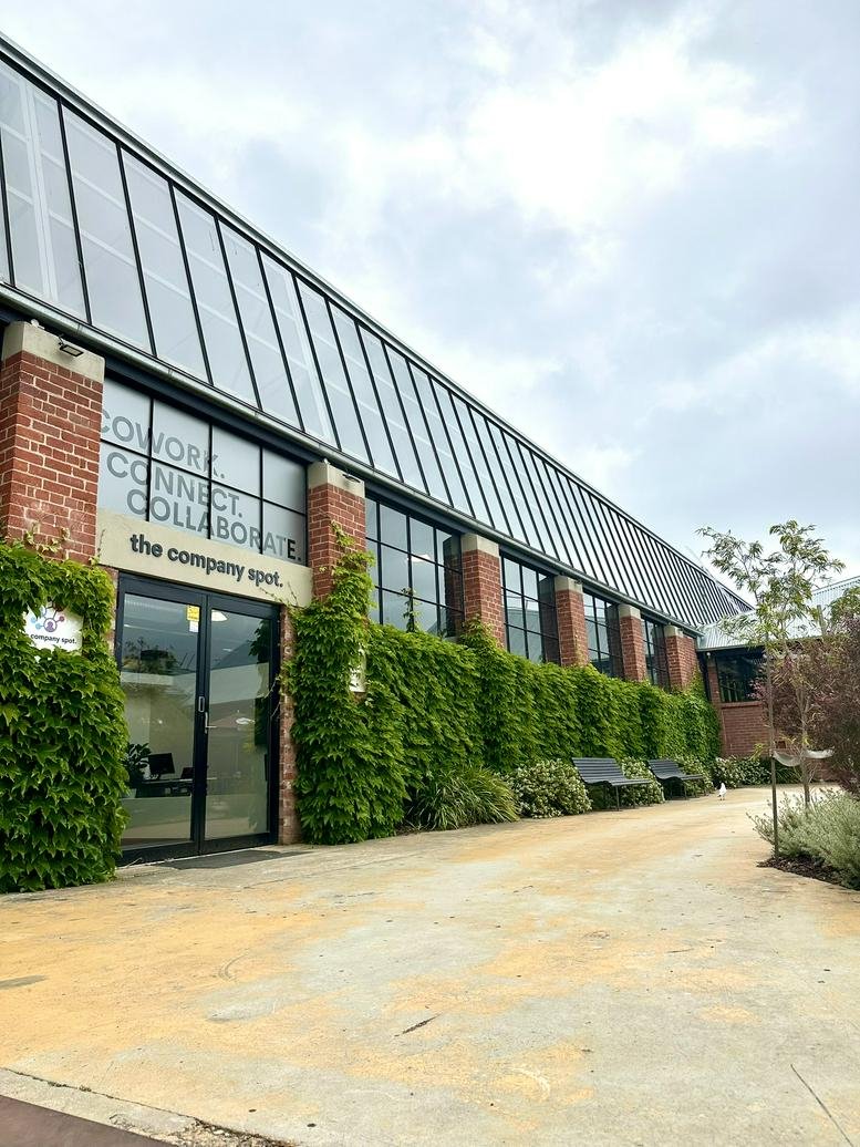 Modern industrial exterior of the company spot featuring red brick and large glass windows.
