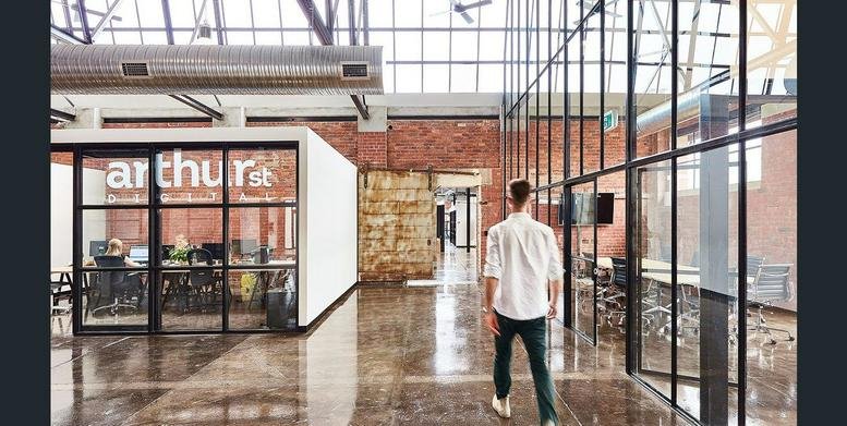 Wide view of a bright industrial-style office with polished floors and glass partitions.