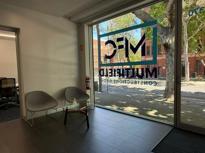 Reception area at 366-370, Spencer Street, Melbourne, Victoria with grey armchairs and branded glass.