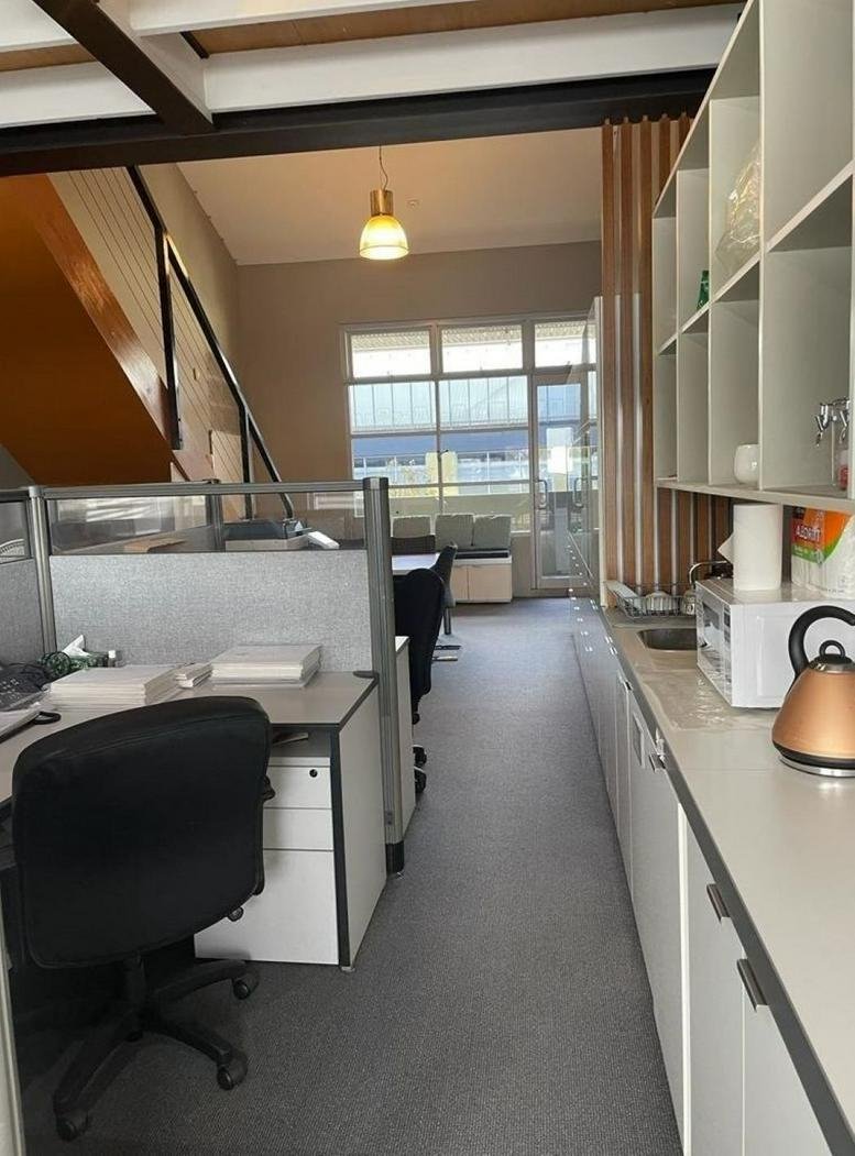 Spacious office interior at the FGS Building featuring workstations and a kitchen area under a loft mezzanine.