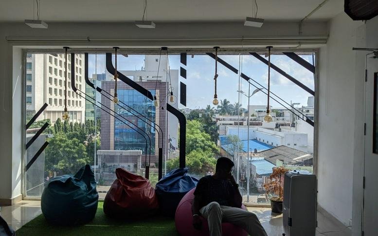 Breakout area at 391A, 3rd floor, Nehru Nagar with bean bags and a large window view of the city.