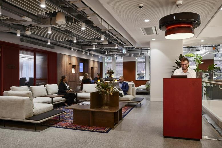 Spacious reception area and lounge at the Henry Davis York Building with exposed ceilings and a red desk.