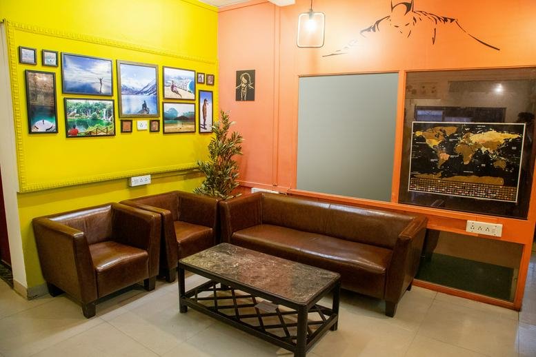 Colorful communal lounge with brown leather seating and framed artwork at 601 B, Annapurna, Adarsh Nagar.