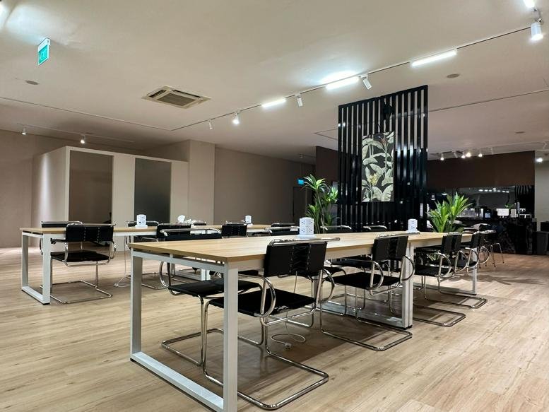 Spacious communal coworking area at SQ Collective with long wooden tables and black chairs.