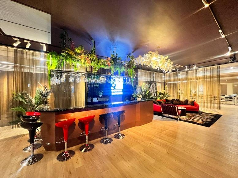 Stylish lounge and bar area with red velvet seating, warm under-counter lighting, and greenery.