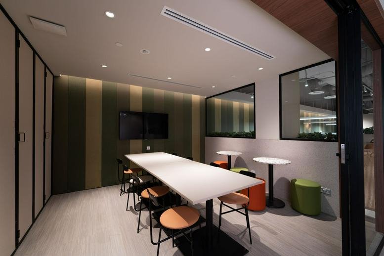 Spacious meeting area with a long white table and colorful stool seating at 71 Woodlands Avenue 3.