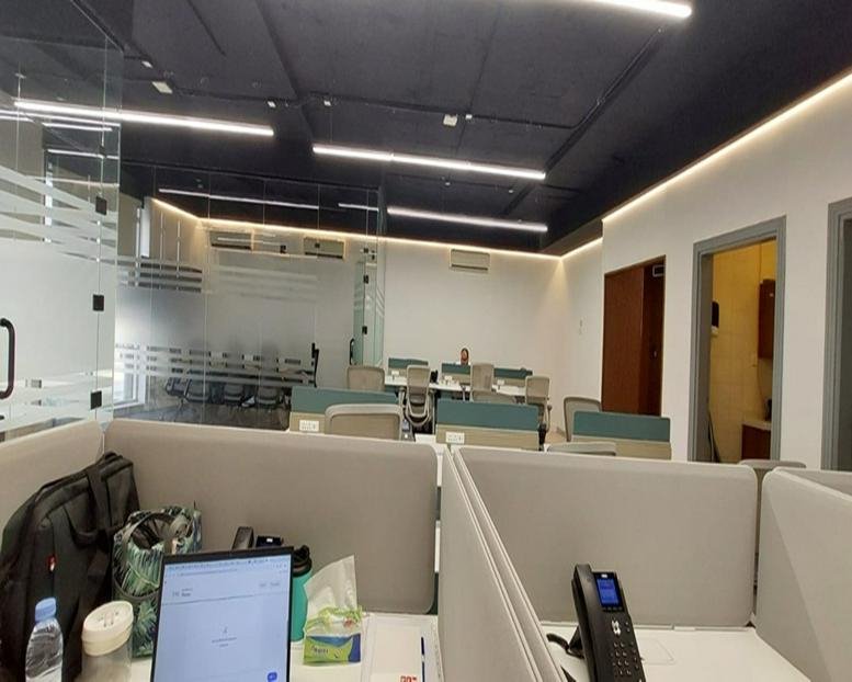 Spacious open-plan workspace at 7488, Al Thoumamah Road with modern workstations and sleek black ceilings.