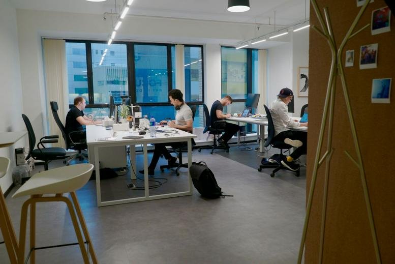 Open-plan office space at Workintong Tower with employees working at white desks near large windows.