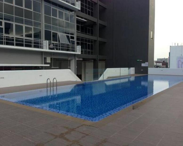 Exterior view of the modern glass-fronted building at 82 Lorong 23 Geylang featuring a rooftop swimming pool.