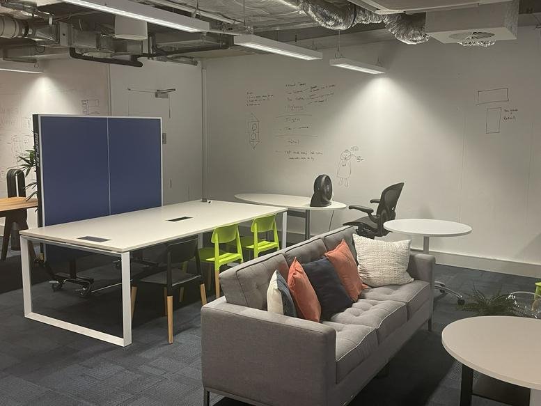 Modern open-plan workspace at 99 York Street, Sydney CBD featuring a grey sofa and large shared white desk.