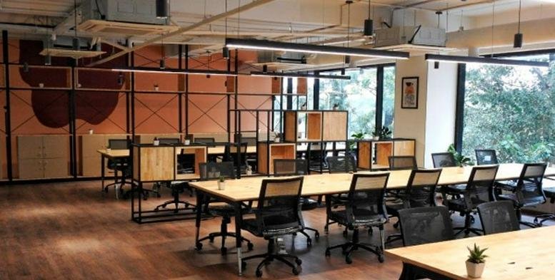 Spacious communal breakout area with long shared tables and an industrial-chic orange feature wall.