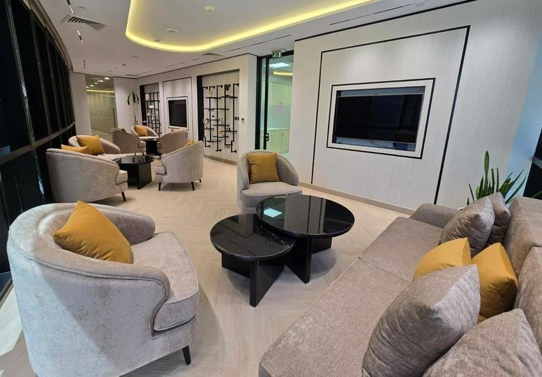 Spacious communal lounge at Bay Tower II with plush armchairs and sleek circular coffee tables.