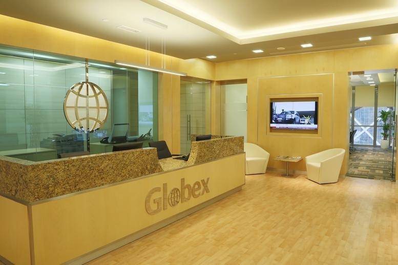 Warmly lit reception area at Bay Tower II featuring a branded wood-paneled desk and white armchairs.